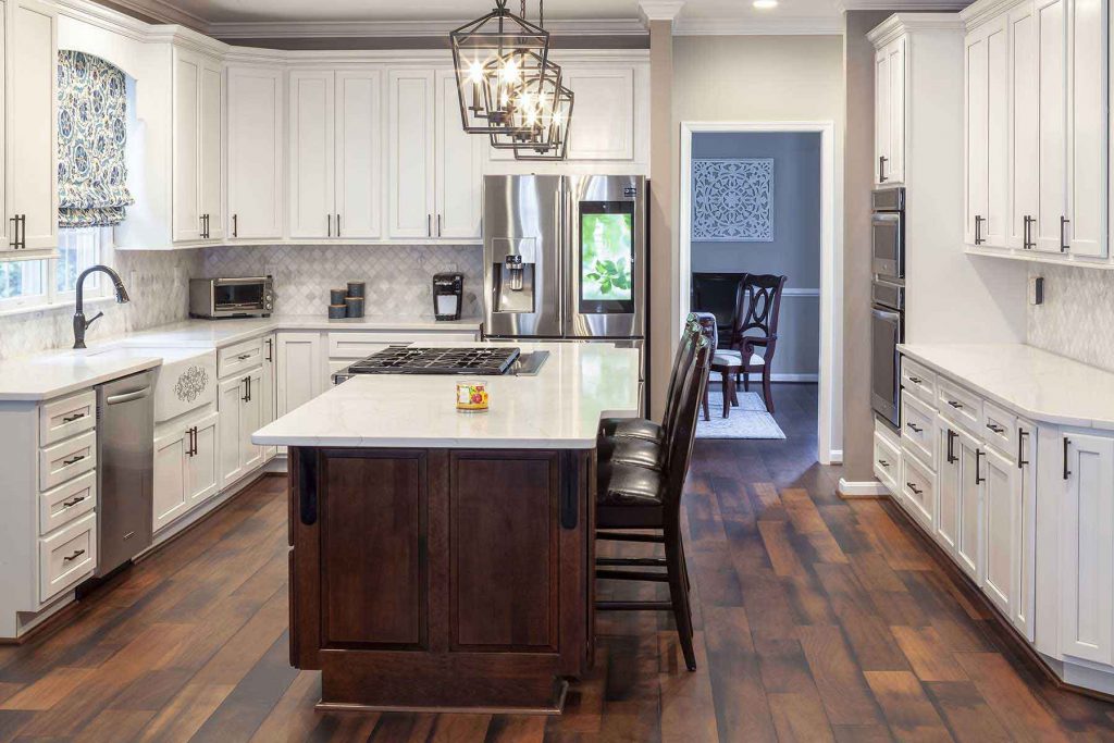 Beautifully remodeled kitchen with dark hardwood flooring, white cabinets, and amazing pendant lights