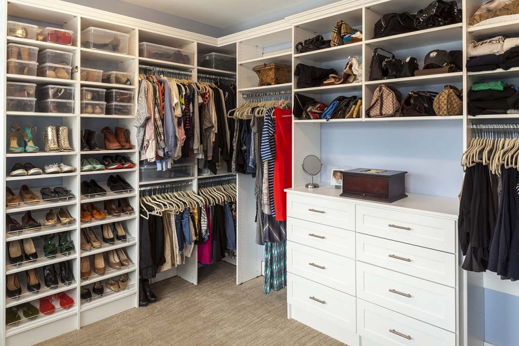 Walk-in closet organized with shelves, drawers, and hanging bars