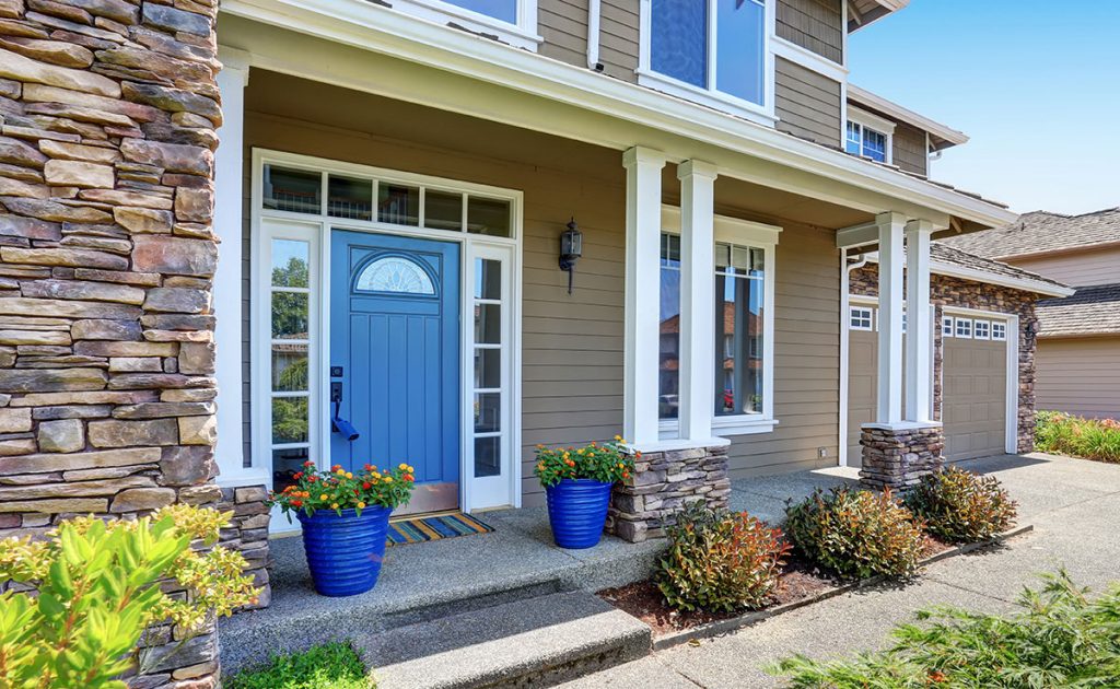 Front porch with blue front door and stone and wood siding that provides a lot of curb appeal.