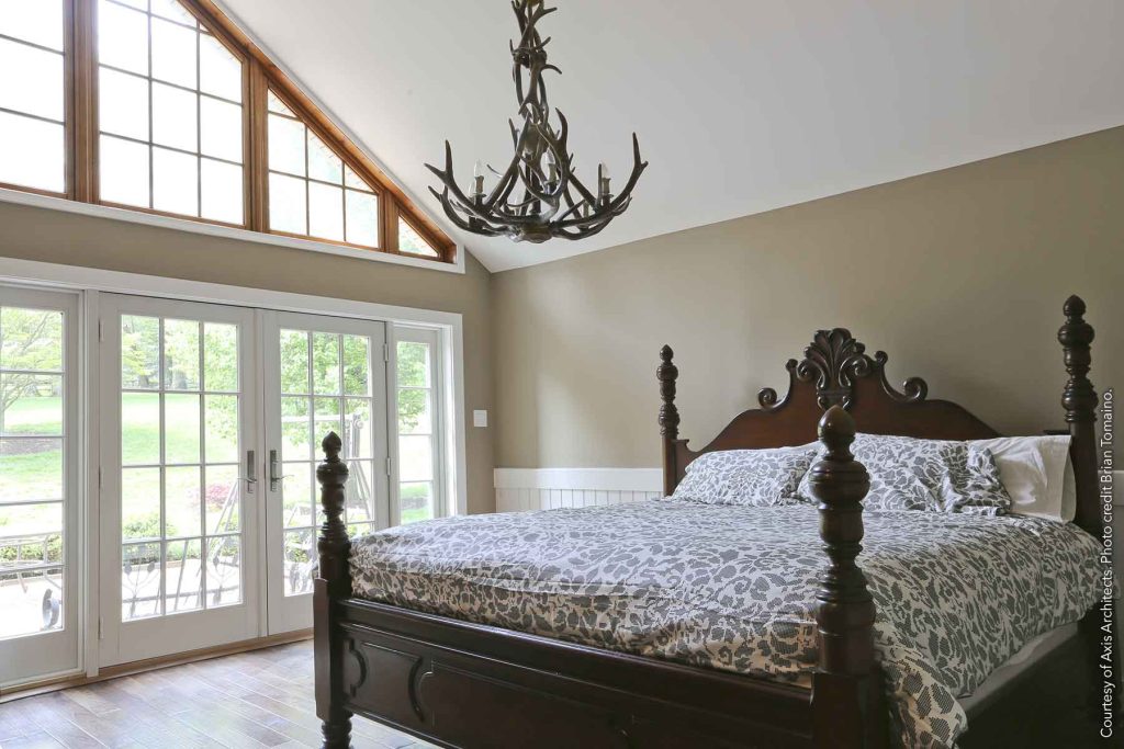 Bedroom with hardwood floors, floor-to-ceiling windows, and an antler chandelier.