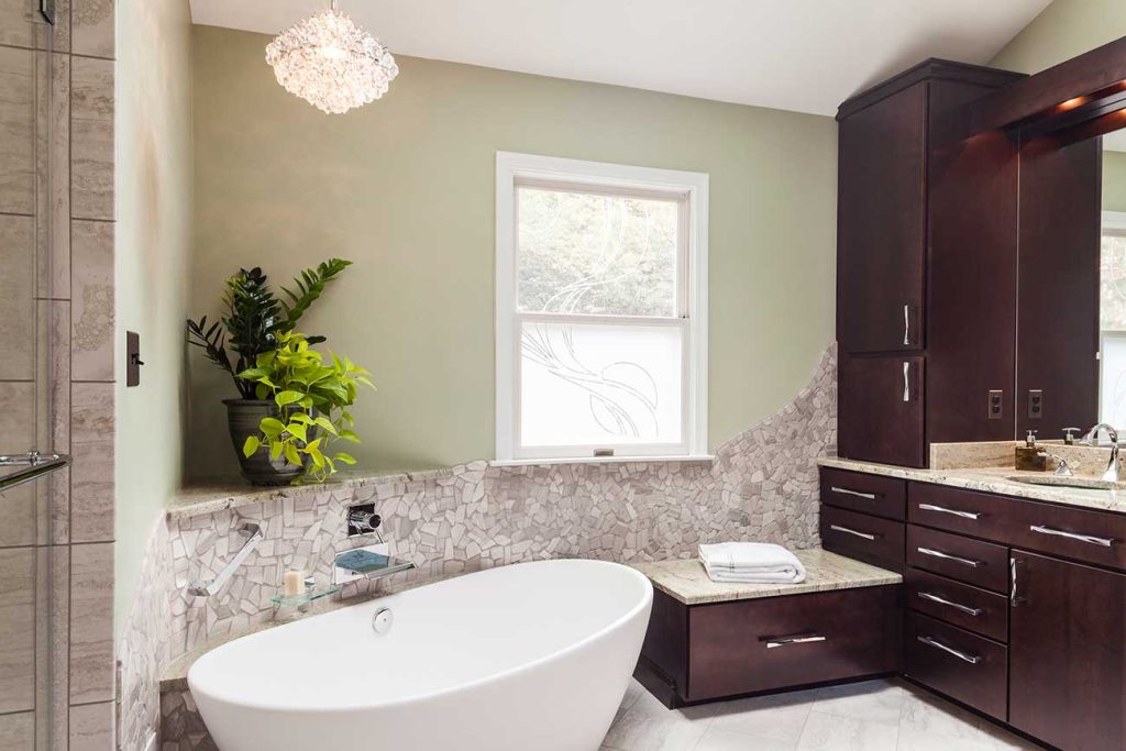 Luxury bathroom with freestanding soaking-tub, dark-wood vanity, and custom tilework on the lowe half of the walls.