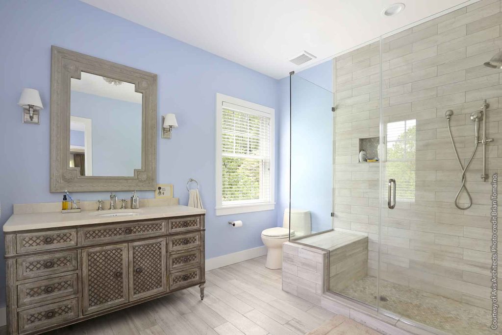 Bathroom design with pastel blue walls, a furniture-style vanity, and modern shower with all glass surround.