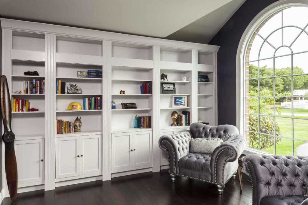 Home library and reading room with floor-to-ceiling bookcases and a large window for natural light