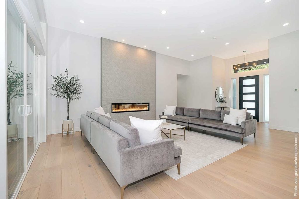 Modern living room in minimalist design style with simple modern fireplace and facing modern sofas in light gray.