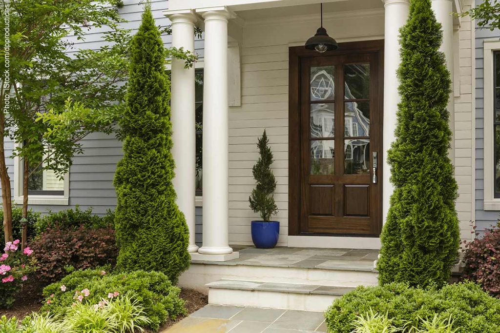 A great remodeling idea is adding a new front door like this dark wood front door with white pillars, steps in the entry way