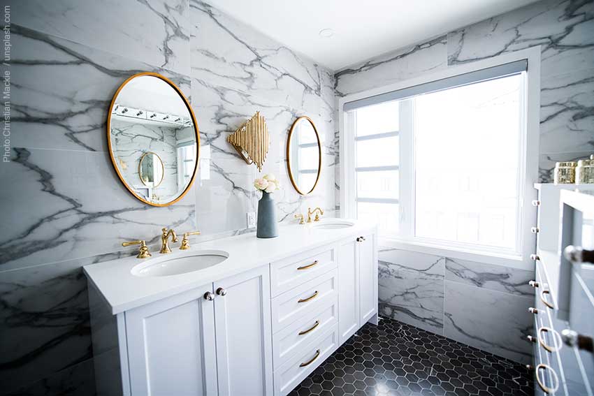 Elegant powder room design with marble tile walls and round mirrors