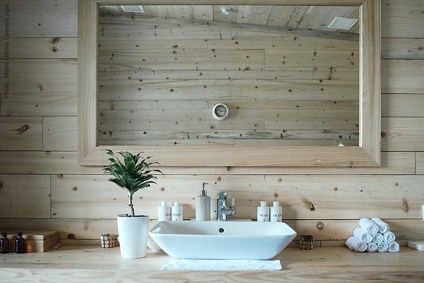 rustic powder room design with natural wood planking on the walls and natural wood frame around large rectangular mirror