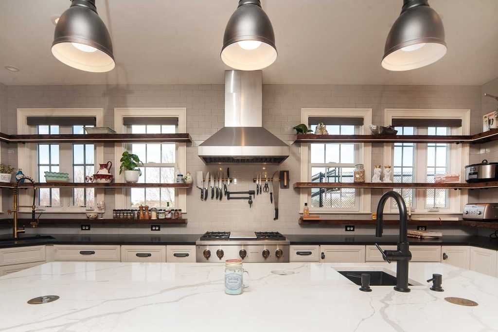 Following a popular kitchen trend, this industrial style kitchen uses open shelvels, a large island, and industrial style  lights