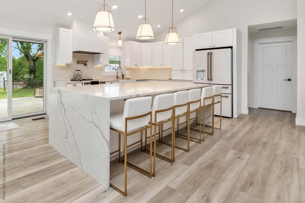 Modern white kitchen with a large island that has a waterfall countertop and lots of prep space