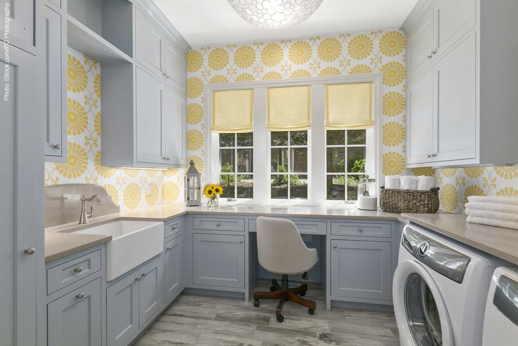 Laundry room with desk and chair, a large farmhouse sink, and yellow flower shapes on walls