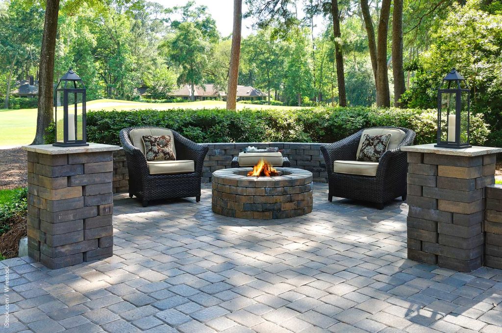 Patio surrounded by a low wall with firepit and chairs in the middle