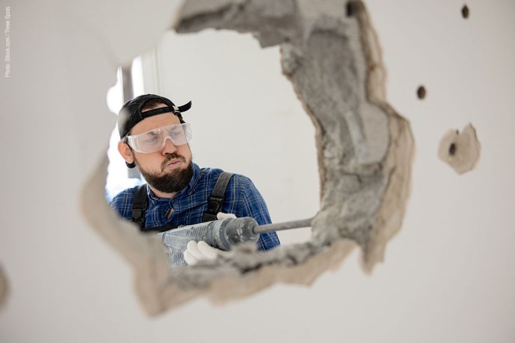 Demolition and rearrangement work. A worker with an impact hammer destroying a wall.